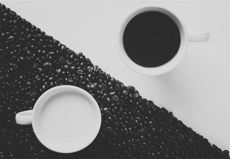 Free Image of Two cups with coffee and milk divided by coffee beans 