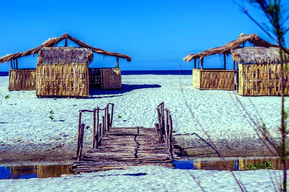 Free Image of Beach huts and wooden bridge on a tranquil sandy beach 