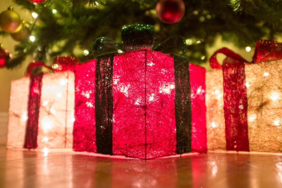 Free Image of Festive Christmas presents glowing near a decorated tree 