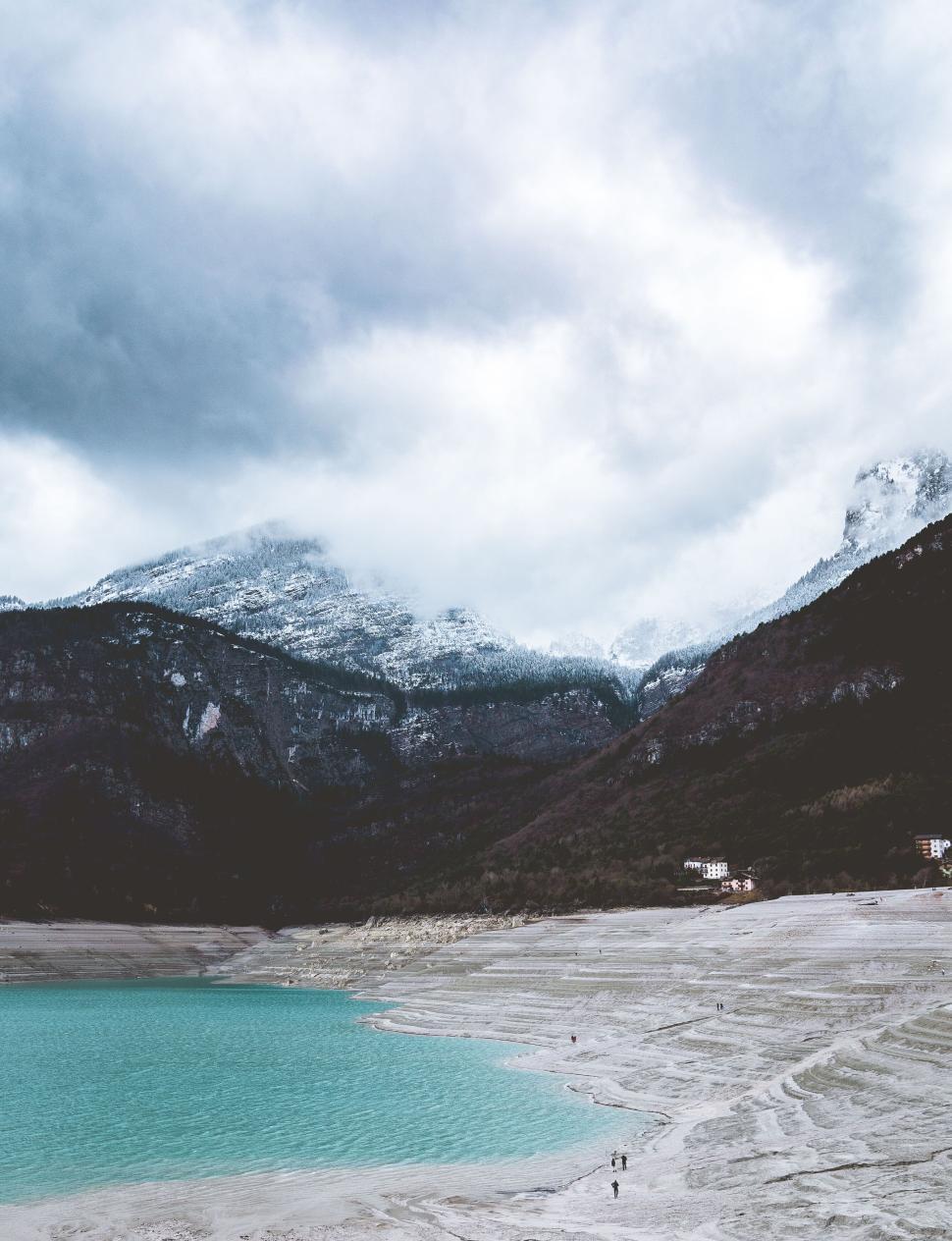 Free Image of Turquoise lake with snowy mountain under overcast sky 