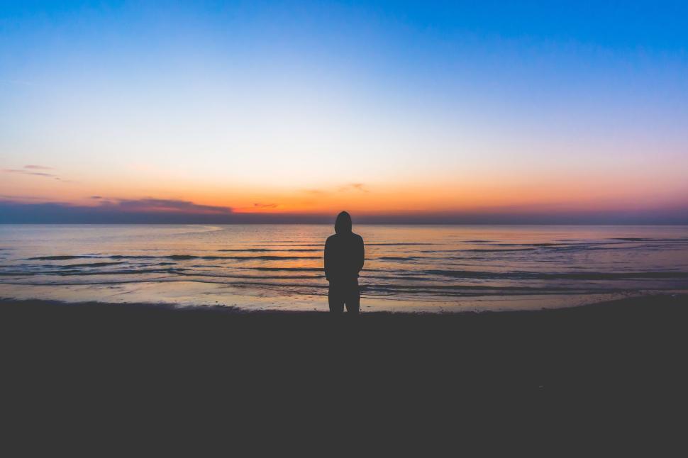 Free Image of Person silhouetted by serene beach sunset at horizon. 