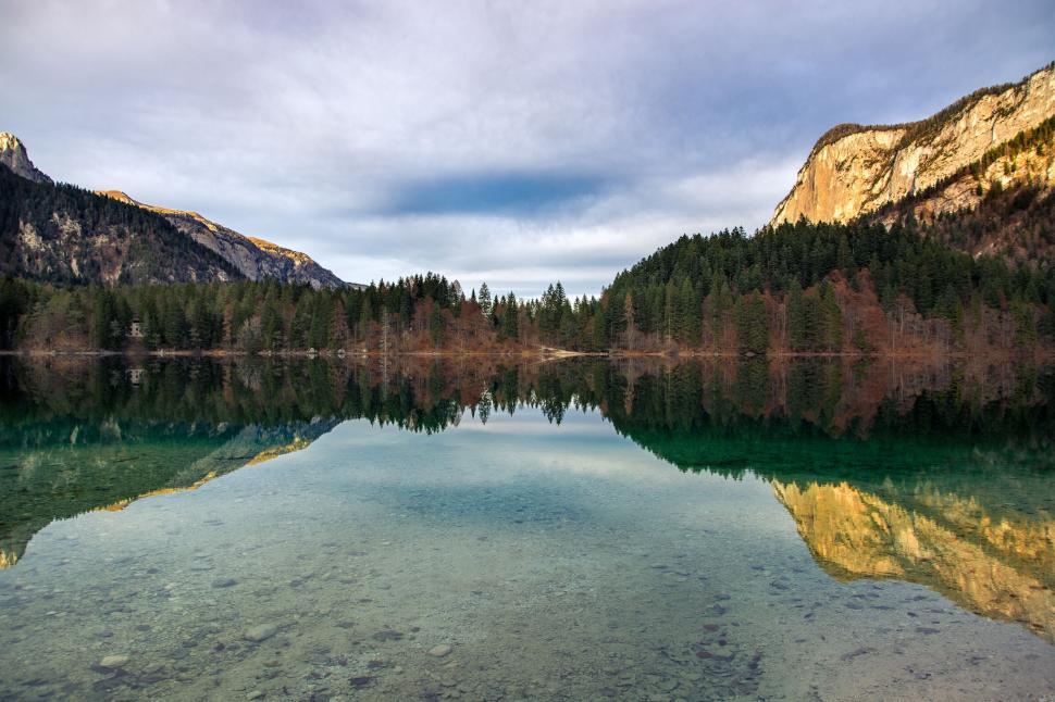 Free Image of Mirror-like lake surrounded by mountains and woods. 