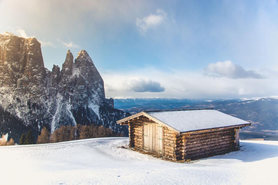 Free Image of Cozy cabin with snowy mountain backdrop at sunrise 