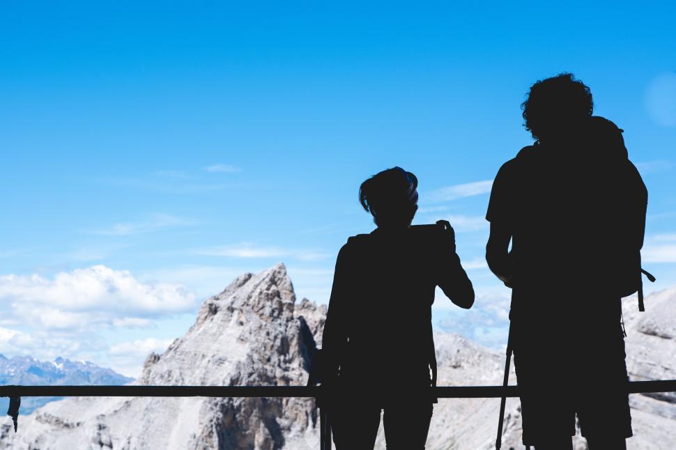Free Image of Two hikers silhouetted against a mountain backdrop 