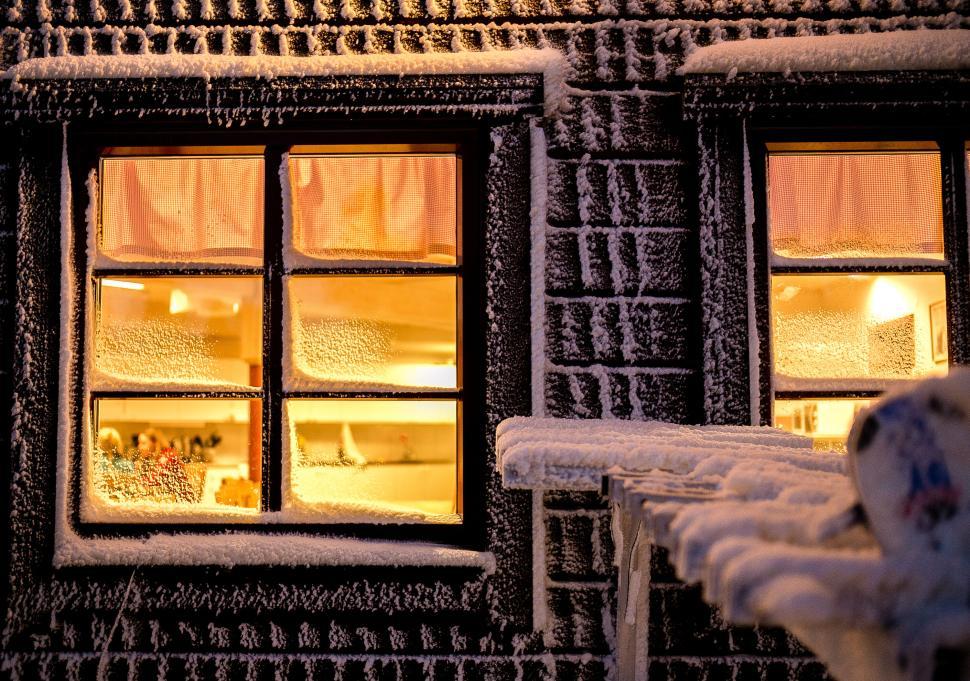 Free Image of Cozy cabin with glowing windows and snow outside 