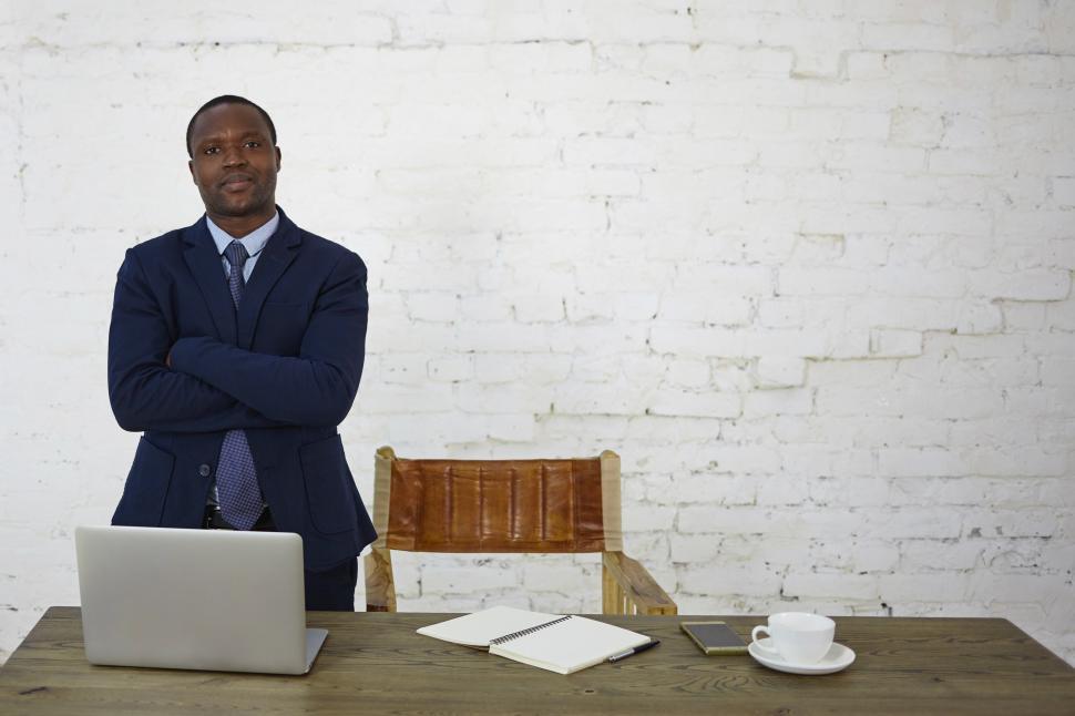 Free Image of Stylish successful African American male entrepreneur having confident look standing at his workplace against white brick wall background with copy space for your text or promotional information 