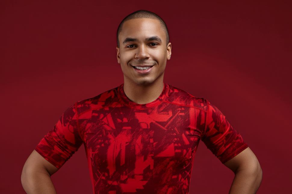 Free Image of People, style, sports and fashion concept. Cropped shot of positive well set young African American male in his twenties posing in studio wearing trendy red t-shirt, looking and smiling at camera 