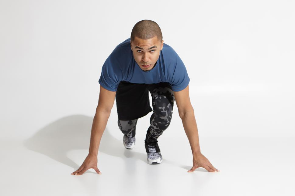 Free Image of Serious mixed race man standing in steady position, preparing to run. Muscular dark skinned male runner ready for running exercise. Health and active lifestyle. Sport, fitness, energy concept 