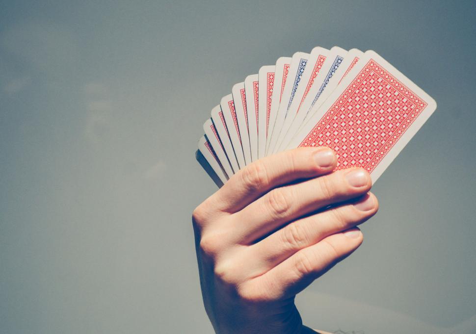 Free Image of Hand holding fan of playing cards against a gray background 
