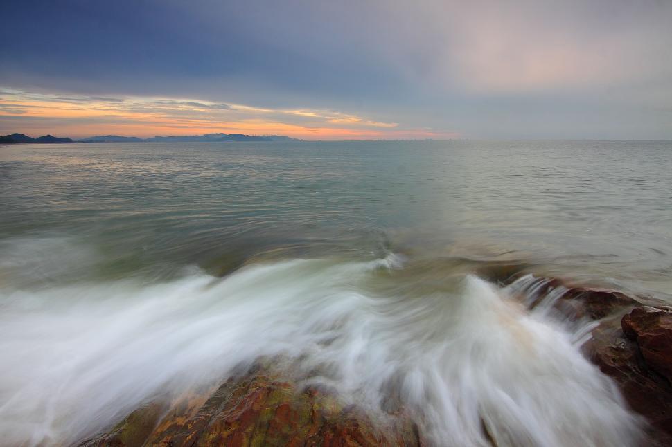 Free Image of Ocean waves crashing against rocks during sunset 