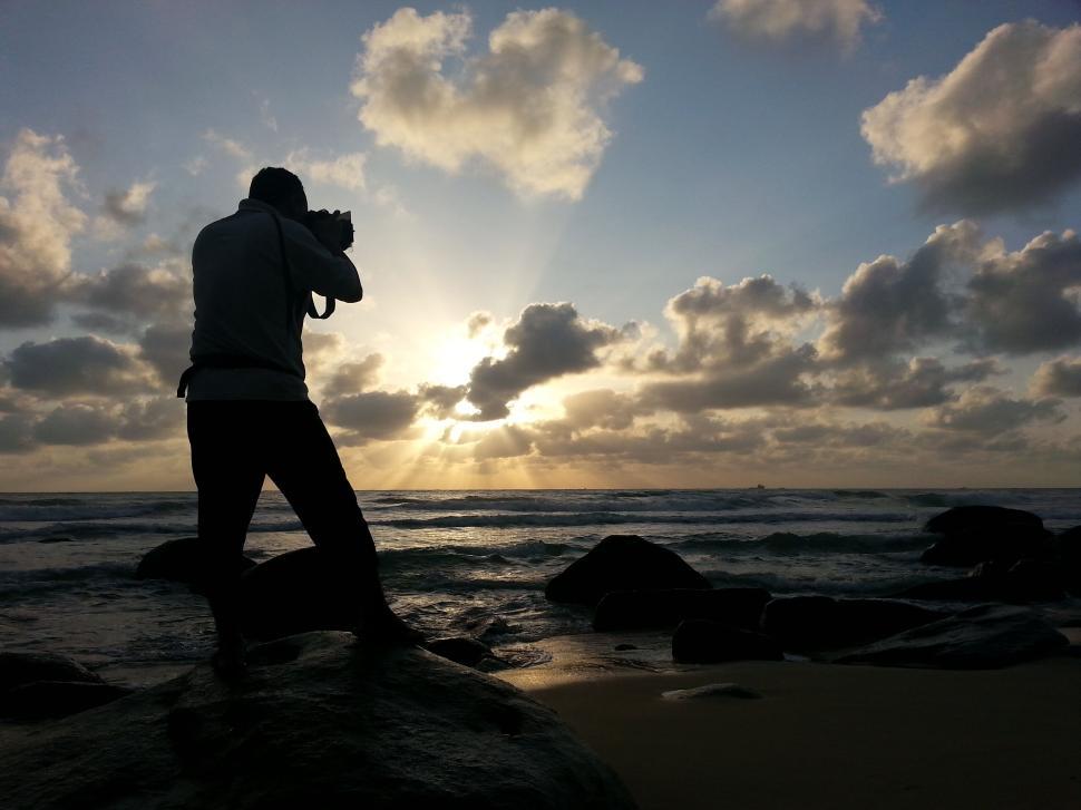 Free Image of Silhouette of photographer capturing ocean sunrise view 