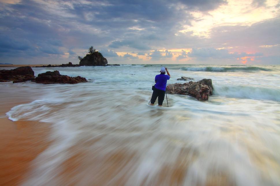 Free Image of Photographer standing in ocean capturing dynamic waves 