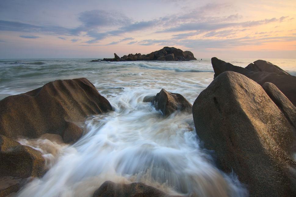 Free Image of Ocean waves splashing against rocks during sunset time 
