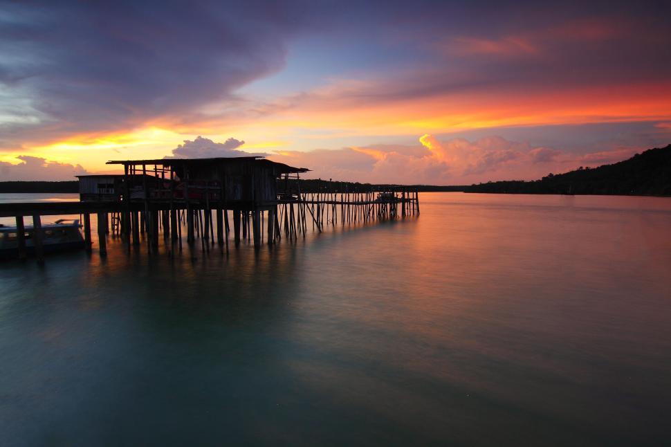 Free Image of Sunset over wooden pier on tranquil water landscape 