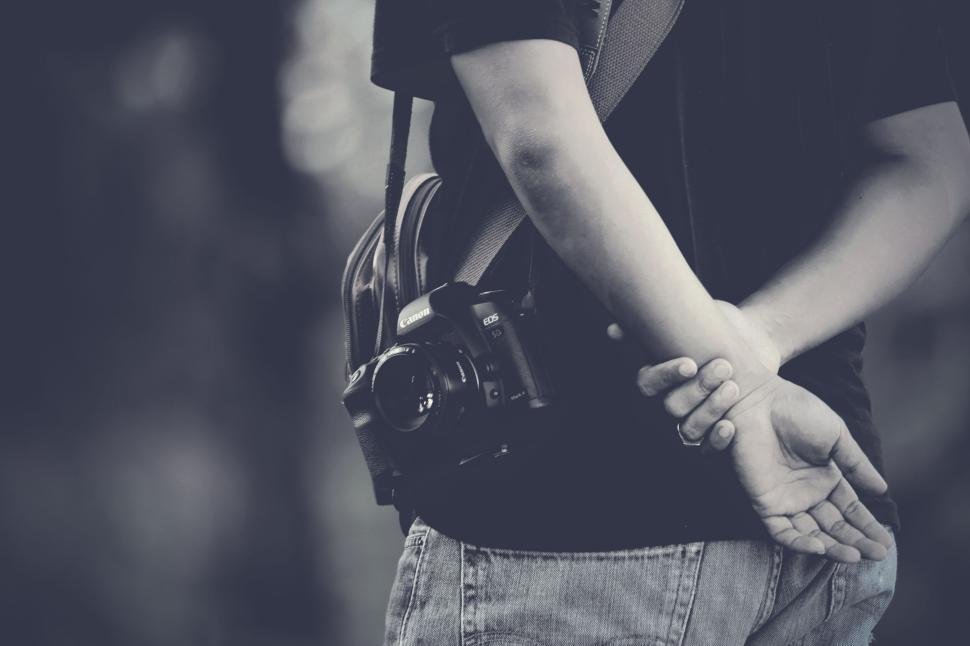 Free Image of Person with camera hanging on shoulder standing outdoors. 