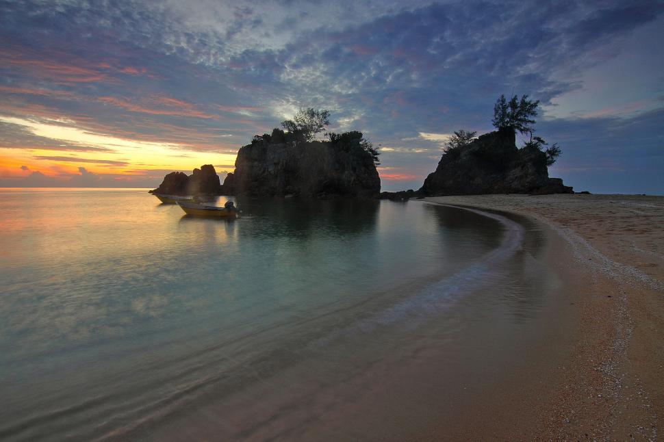 Free Image of Beautiful sunset over secluded beach with calm waters 
