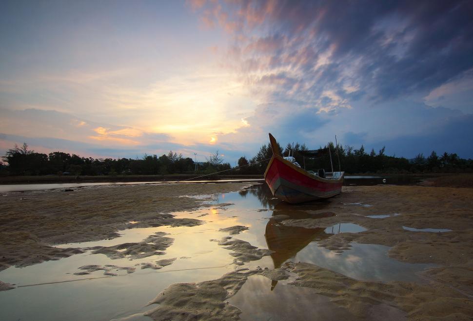Free Image of Tranquil boat on reflective beach during sunset dusk 