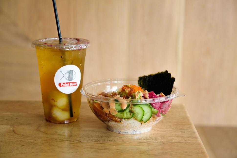 Free Image of Glass of iced tea next to poke bowl with fresh ingredients 