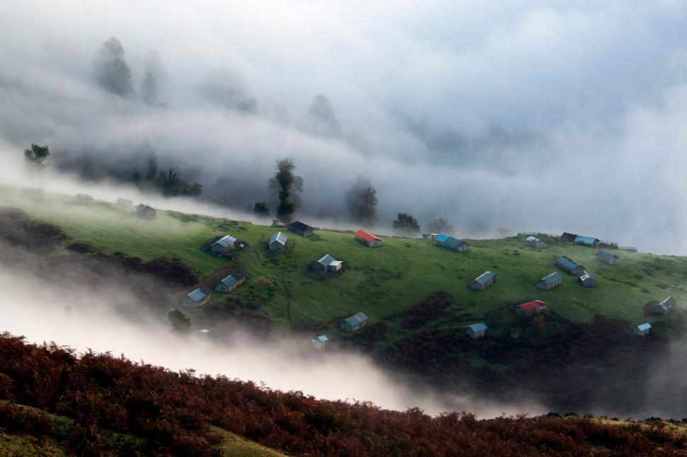 Free Image of Village houses in misty hillscape with lush greenery around 