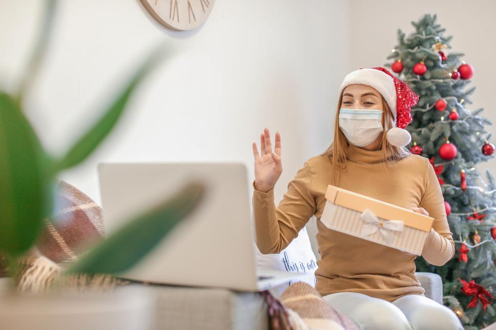Free Image of Woman video-calling with gift during Christmas season. 