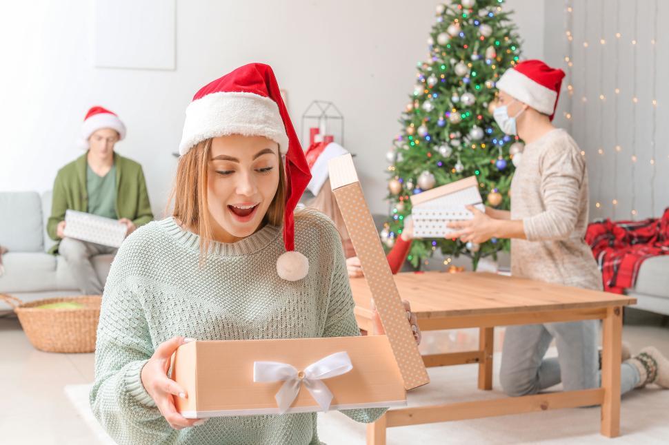 Free Image of Excited Woman Unwrapping Christmas Present Near Tree. 