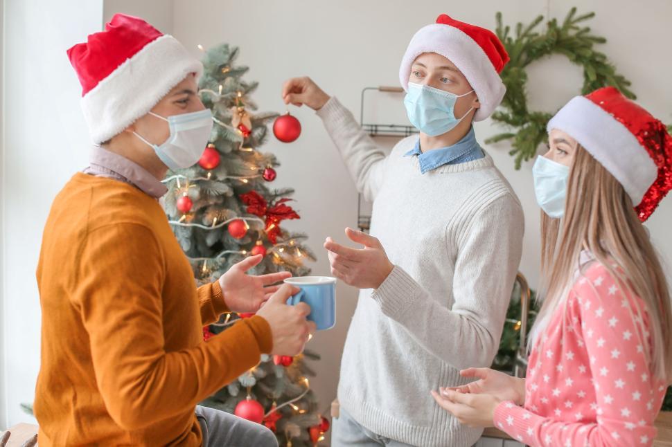 Free Image of Friends decorating Christmas tree and sharing coffee. 
