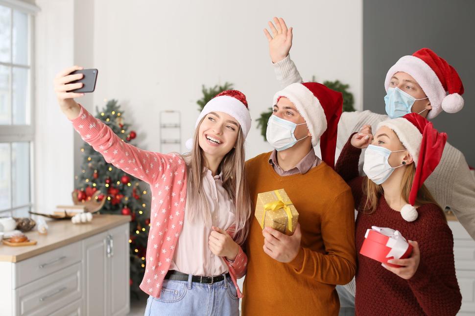 Free Image of Friends take holiday selfie with masks and Santa hats 