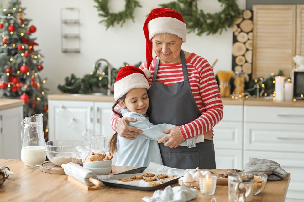Free Image of Grandmother and granddaughter hug while baking cookies 