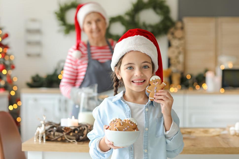 Free Image of Girl with Santa hat holding gingerbread men and cookies 