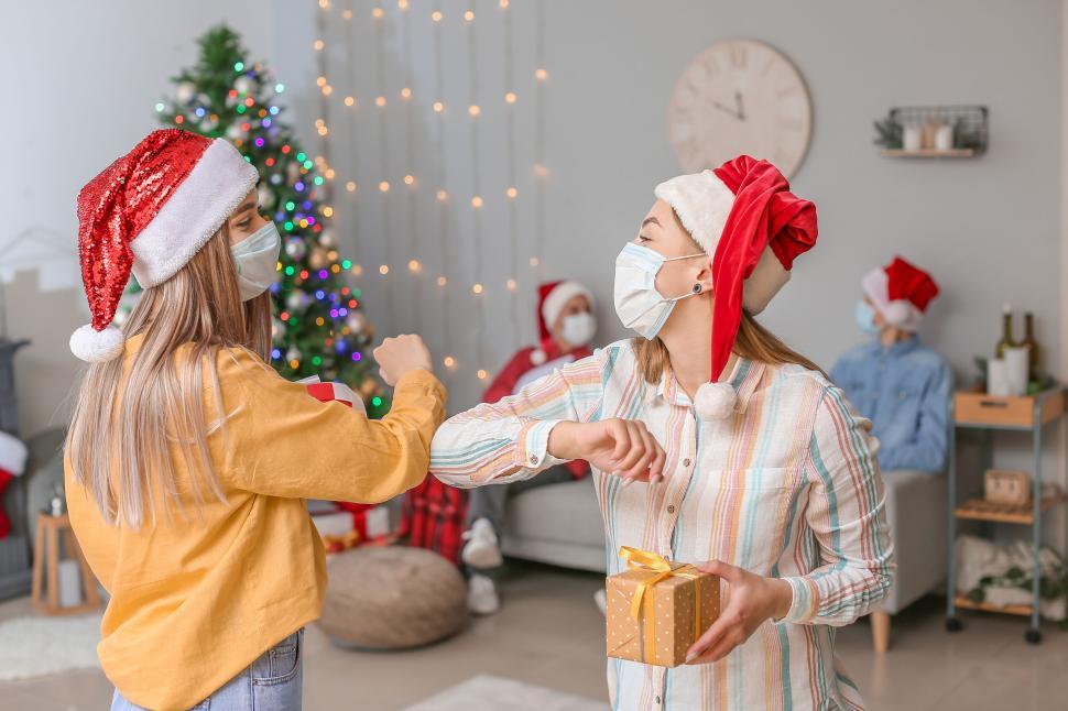 Free Image of Friends exchanging gifts and fist-bumping at Christmas. 