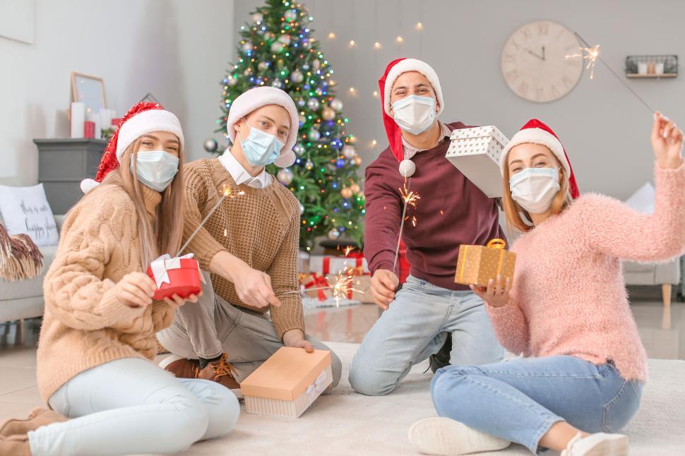 Free Image of Four friends celebrate Christmas with sparklers and presents 