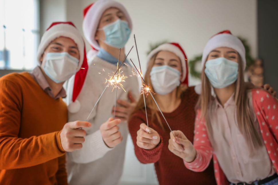 Free Image of Friends with face masks hold sparklers in holiday cheer 