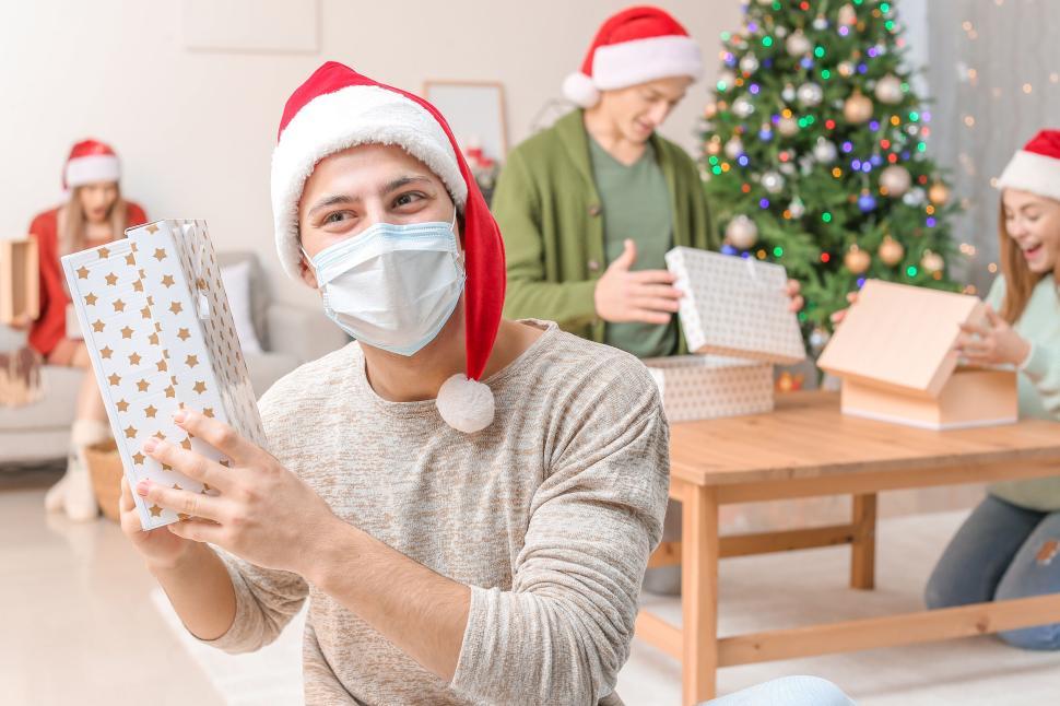 Free Image of Friends unwrapping gifts under decorated Christmas tree 