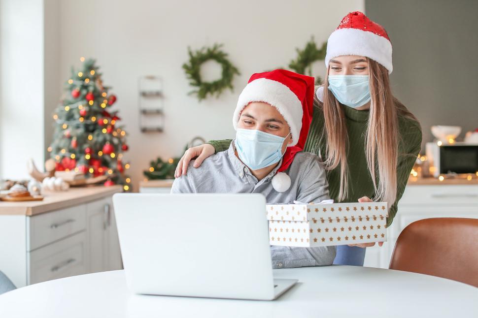 Free Image of Masked couple with gift having festive virtual call 