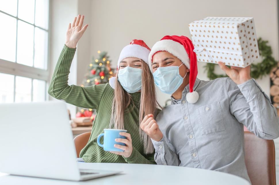 Free Image of Virtual Christmas celebration couple with gift and waving. 