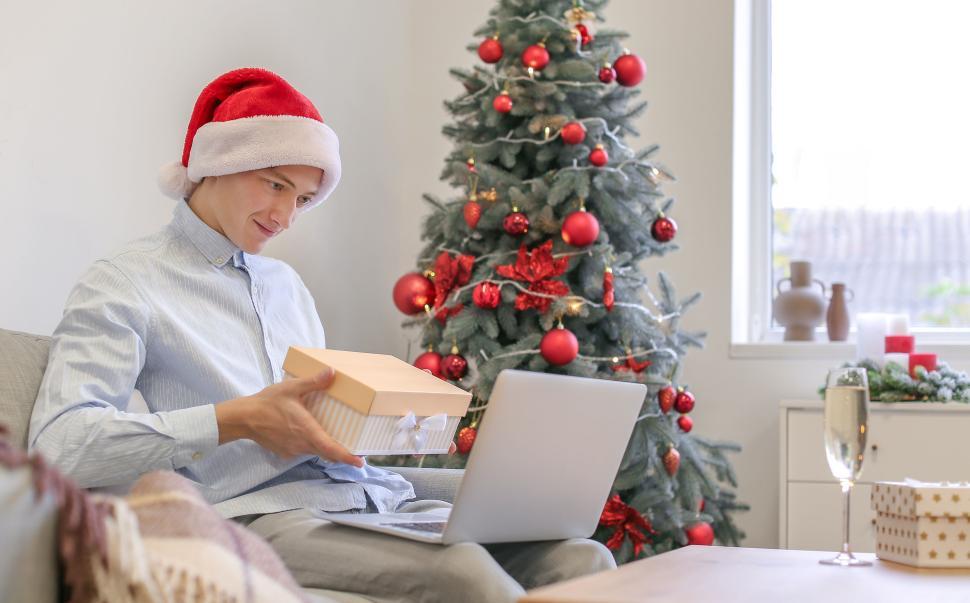 Free Image of Man with gift exchanges presents in decorated room at Christmas. 