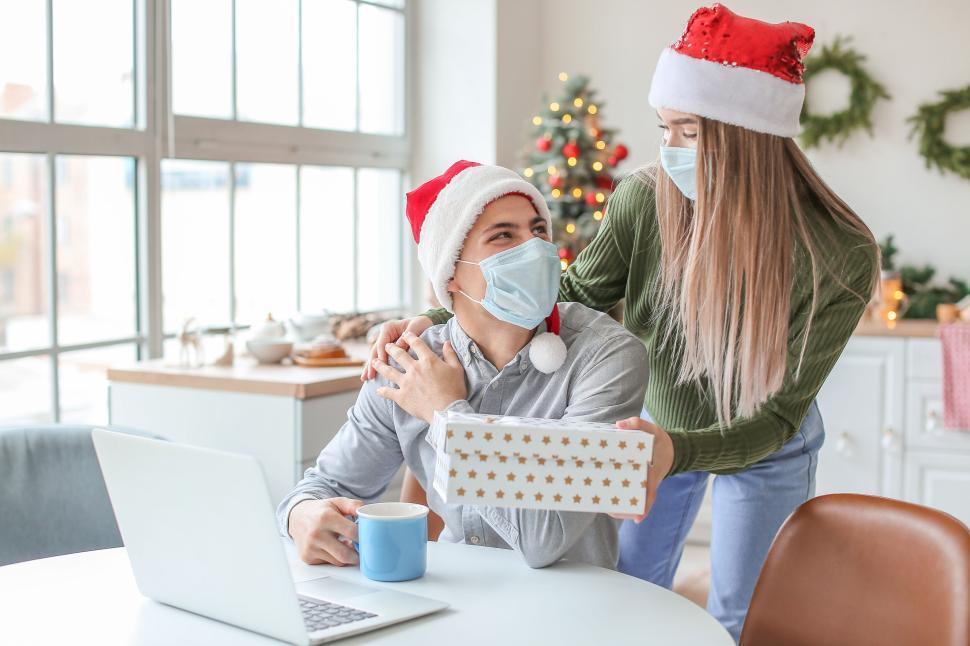 Free Image of Warm holiday morning with couple giving gift and laptop chat. 