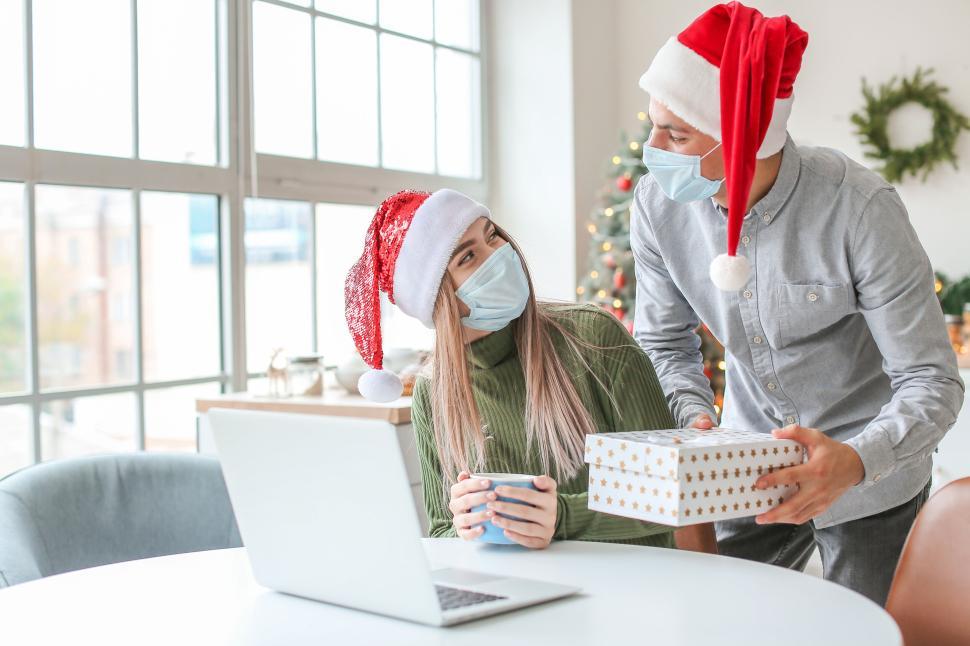Free Image of People with santa hats exchanging gifts indoors 