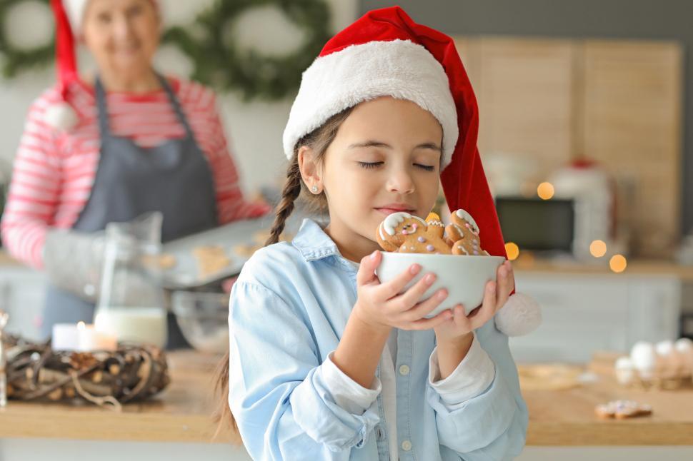 Free Image of Young girl savoring gingerbread cookies in kitchen joyfully 