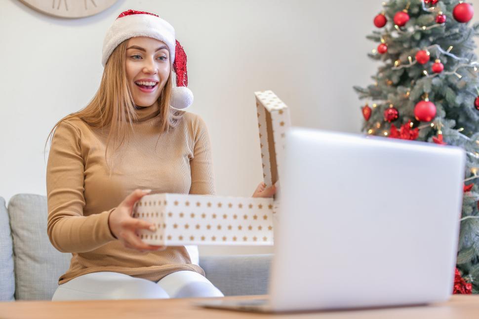 Free Image of Woman opening a Christmas present during video call 