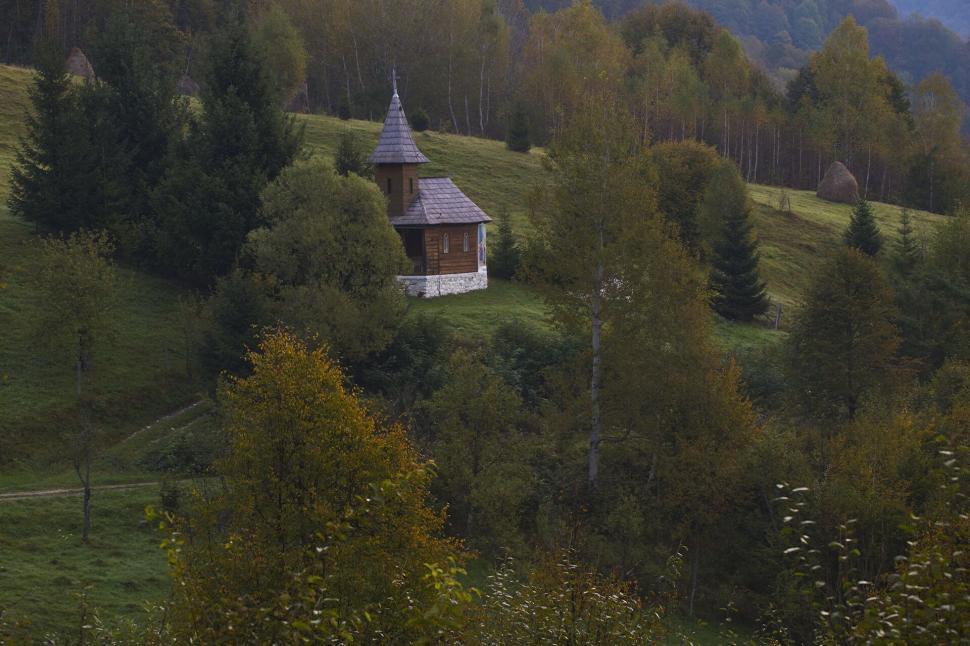 Free Image of Wooden church surrounded by lush greenery and hills 