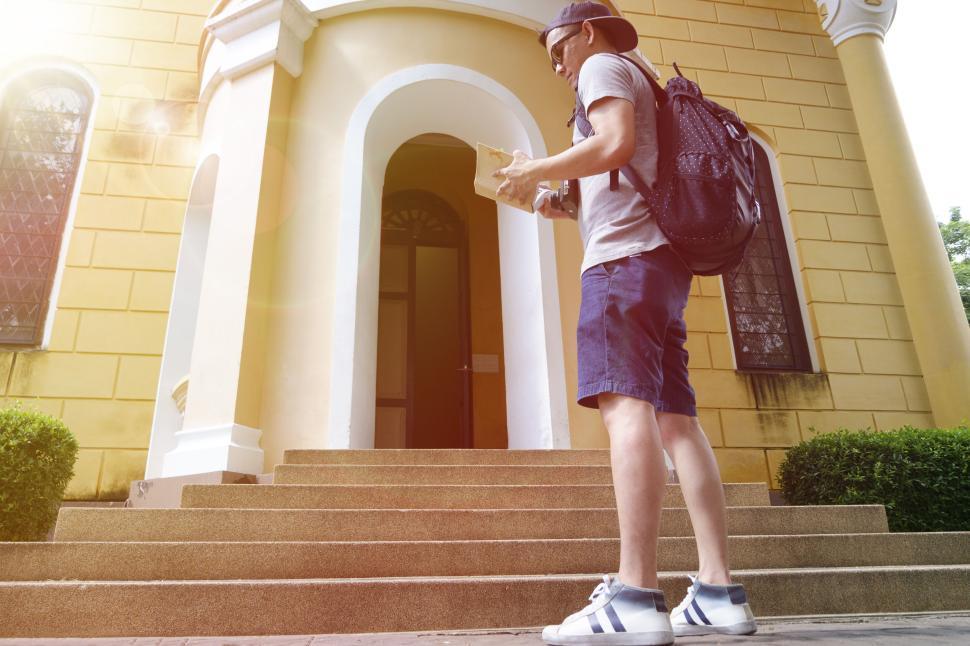 Free Image of Traveler with backpack and map approaching a building. 