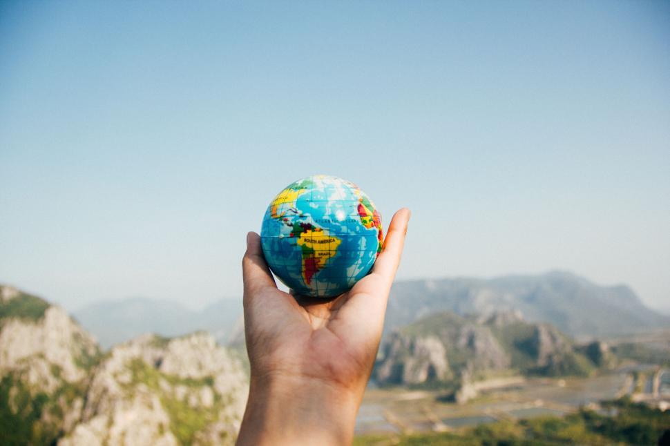 Free Image of Hand holding a miniature globe against a scenic background. 
