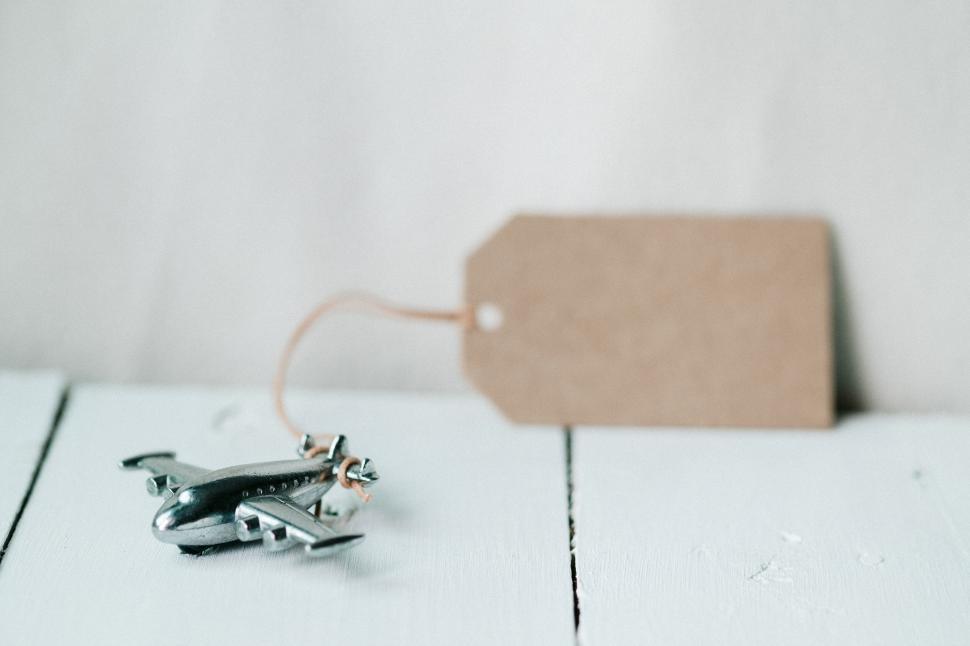 Free Image of Small metal airplane figurine with blank brown tag. 