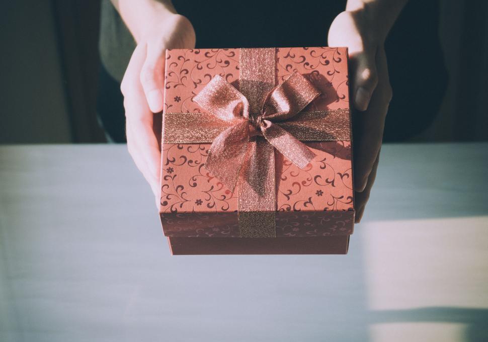 Free Image of Hands holding beautifully wrapped gift box with bow. 
