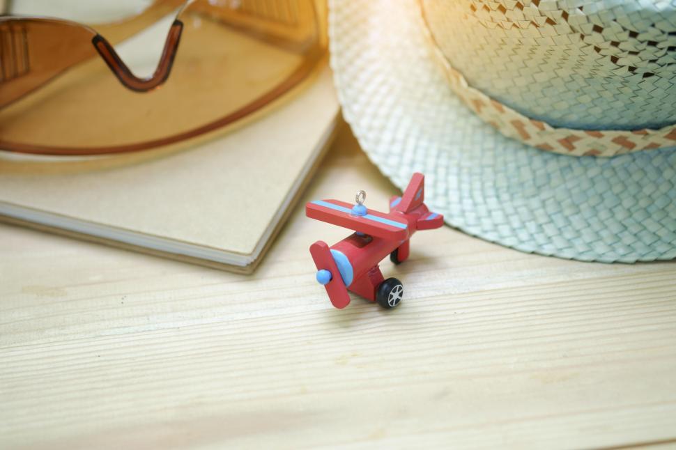 Free Image of Travel items including hat and toy airplane on wooden table. 