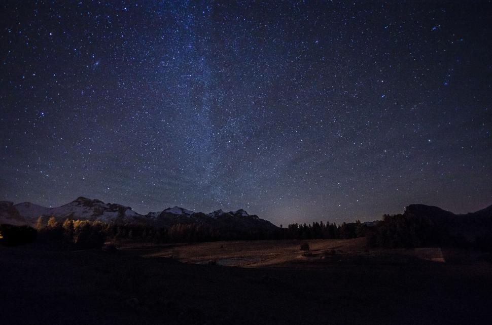 Free Image of Star-filled night sky over a mountain landscape scene 