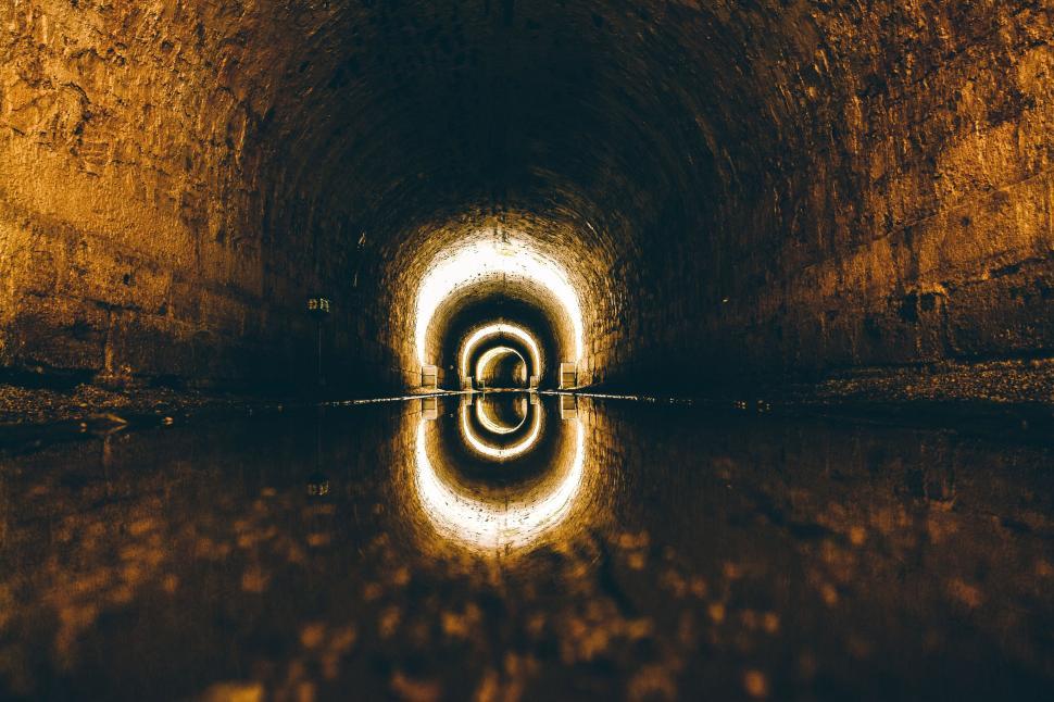 Free Image of Illuminated underground tunnel with reflective water surface. 