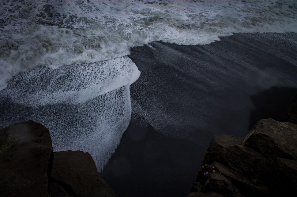 Free Image of Waves crashing onto black sand beach showcasing nature’s fury. 