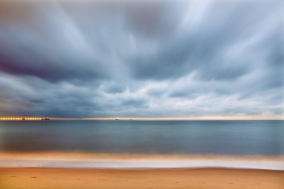 Free Image of Blurred clouds over a still ocean during twilight. 